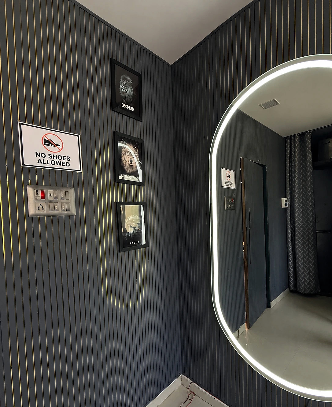A lit oval mirror and framed Discipline, Consistency and Focus prints in the changing room